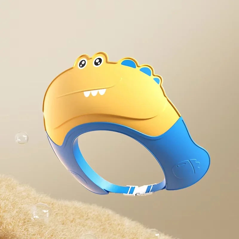 A yellow and blue adjustable baby bath shampoo shield cap with ear protection resting on a fuzzy surface.