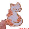 A white cat embroidered patch with peach-colored floral accents on a light fabric background.
