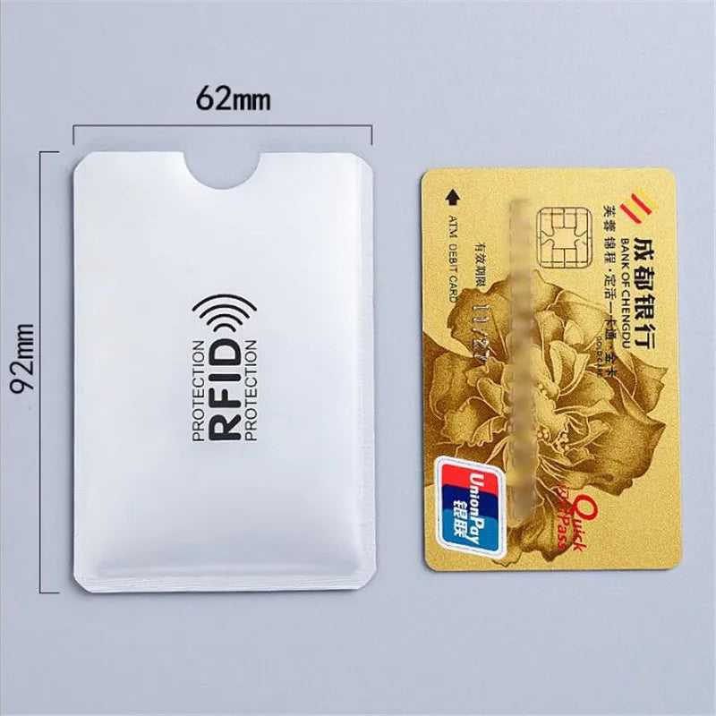 A white plastic card holder with an RFID protection feature next to a gold-colored ATM debit card.