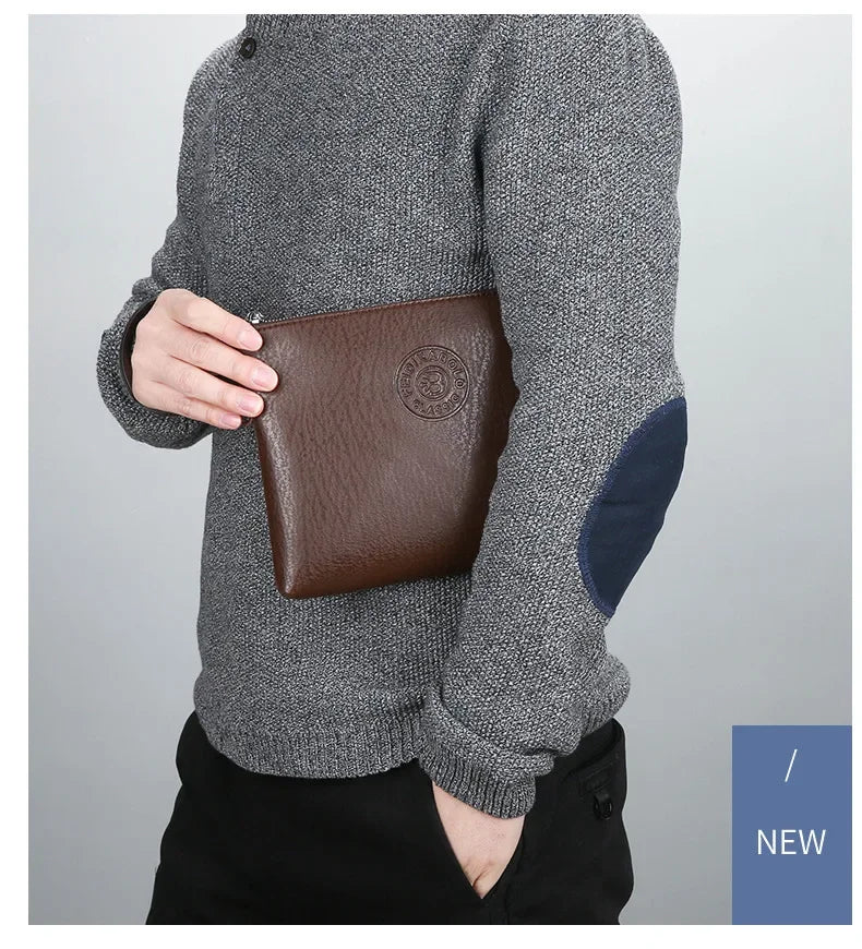 Ein Mann trägt einen grauen Pullover und hält eine braune Ledergeldbörse für Herren.