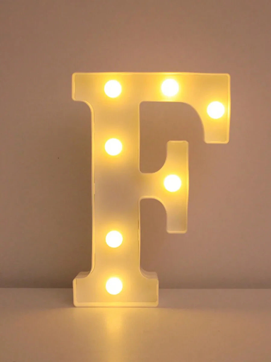 A glowing yellow LED letter F night light mounted on a white surface.