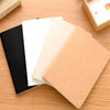 A stack of A6 kraft paper blank notebooks in black, white, and tan on a wooden surface.