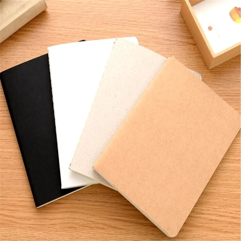A stack of A6 kraft paper blank notebooks in black, white, and tan on a wooden surface.