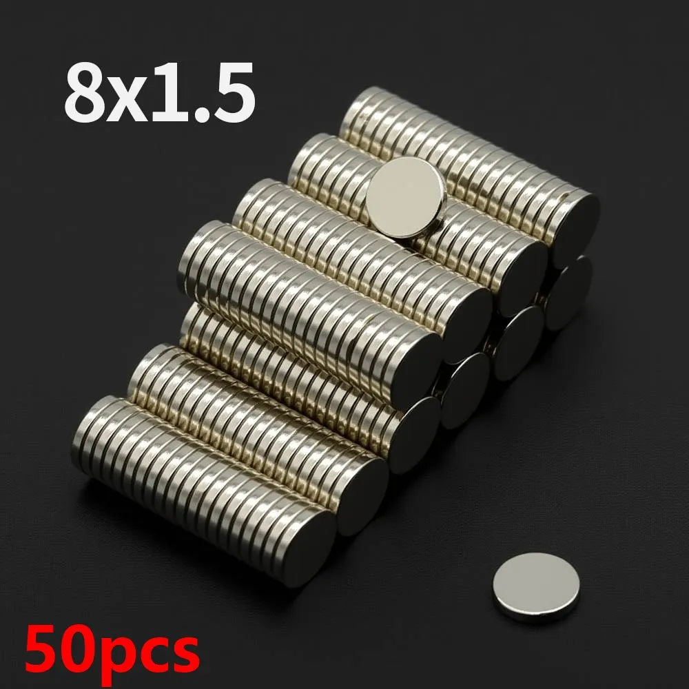 A pile of 50 pieces of 8x1.5 disc neodymium magnets in silver color arranged diagonally on a dark surface.
