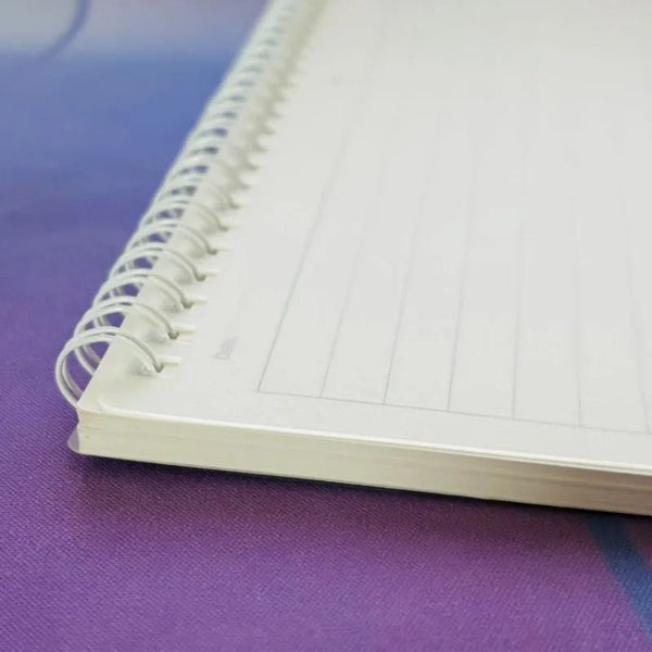 Cuaderno espiral blanco B5 flip-top con papel rayado y divisores de página sobre una superficie morada.
