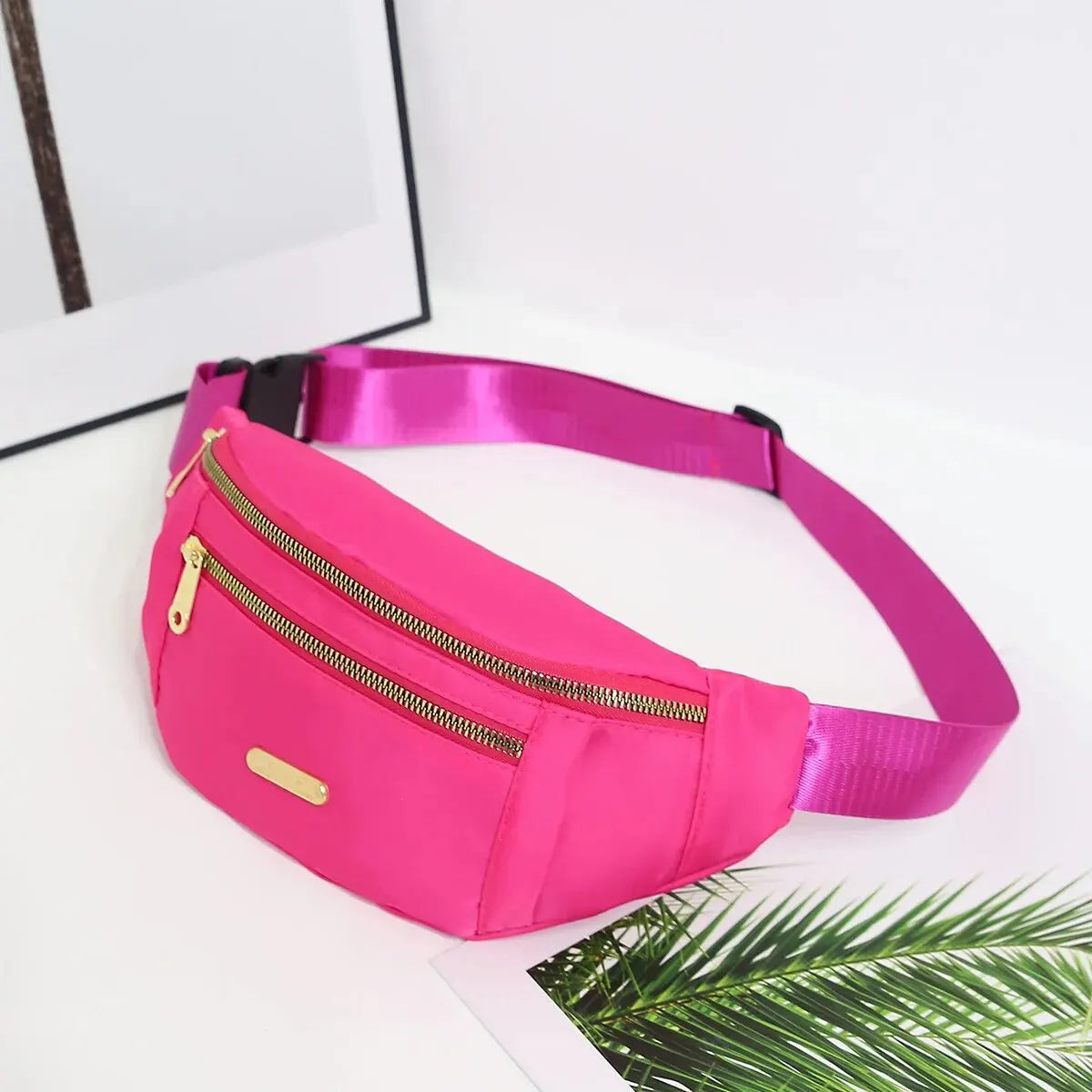 Helle pinke Damen-Sport-Fanny-Pack mit goldener Reißverschluss und rosa Träger auf weißer Oberfläche.