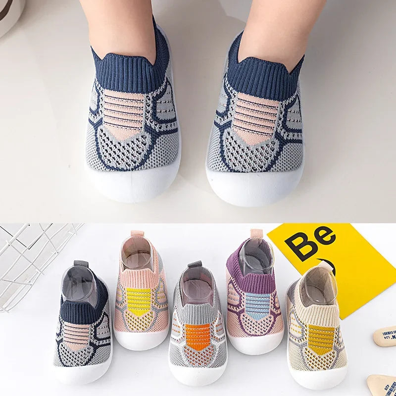 A pair of knitted baby shoes in gray and white with blue accents shown from the top view.