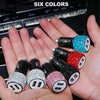 A hand holds six multi-color rhinestone USB car chargers with various colors and designs.