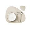 A set of neutral-toned reversible non-slip placemats with a white plate, fork, and spoon.