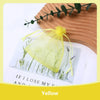 A yellow organza drawstring gift bag filled with dried herbs and greenery, set against a light background.