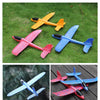 Four foam glider planes in yellow, red, and blue colors resting on green grass.