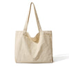 Sac cabas en toile beige suspendu sur fond blanc.