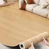 Roll of light wood grain waterproof self-adhesive floor stickers lying on a gray surface.