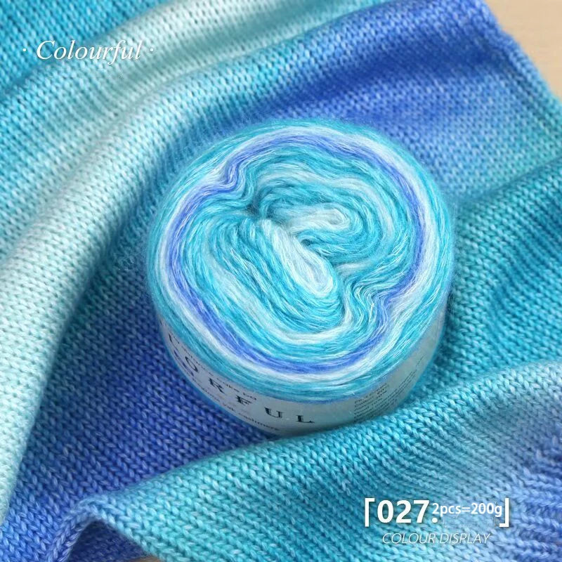 A spool of bright blue and cyan gradient yarn is displayed on a blue fabric background.