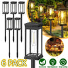 A pack of six black solar path lights with warm glow illuminating an outdoor landscape.