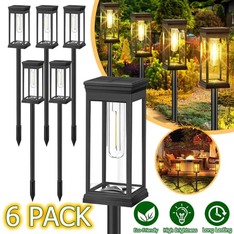 A pack of six black solar path lights with warm glow illuminating an outdoor landscape.