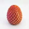 A textured, egg-shaped fidget toy made of pink and orange silicone or plastic.