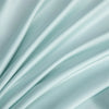 Soft, flowing light blue bamboo flat sheet fabric draped in elegant folds.