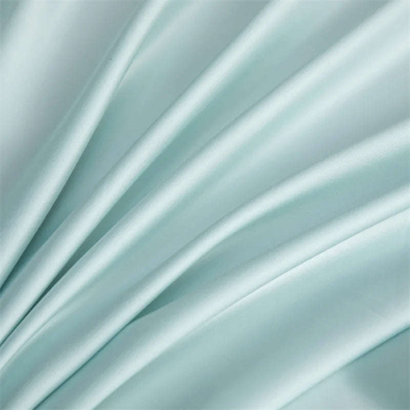 Soft, flowing light blue bamboo flat sheet fabric draped in elegant folds.