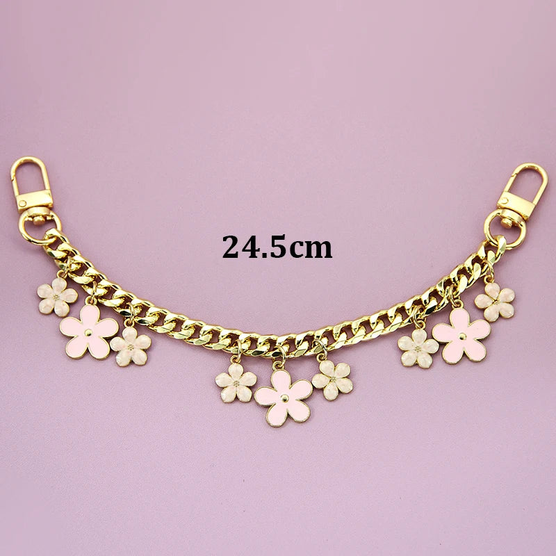 A gold-colored decorative chain phone strap featuring small white flower charms and a lobster clasp.
