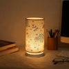 A Nordic retro USB table lamp with a fabric shade emits a warm glow on a wooden surface.