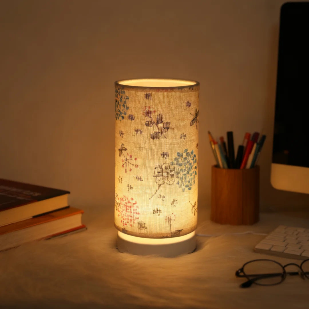 A Nordic retro USB table lamp with a fabric shade emits a warm glow on a wooden surface.