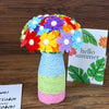 A colorful bouquet of fabric flowers in a glass vase with a greeting card for a creative craft kit