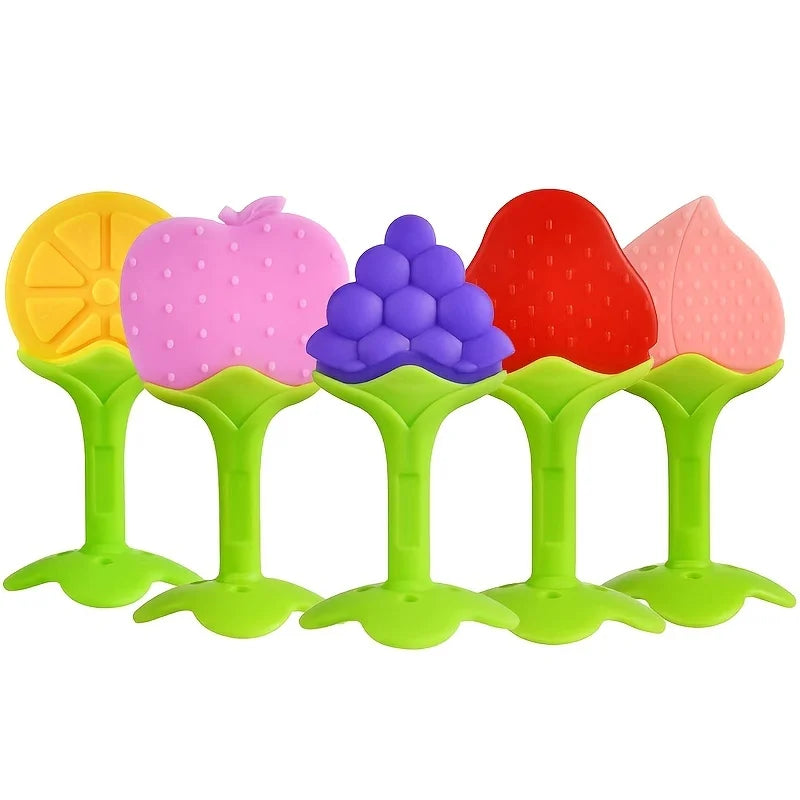 A set of silicone baby teethers shaped like an apple, a bunch of grapes, and a strawberry in pink, purple, and red colors.