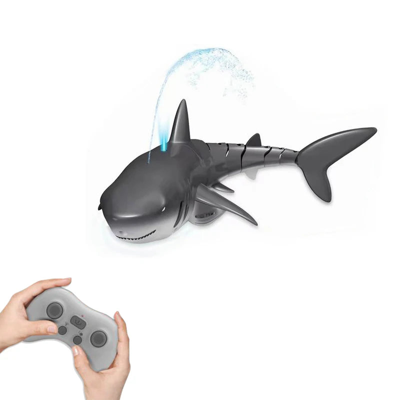 A gray shark toy is shown spraying water, with a hand holding a remote control nearby.