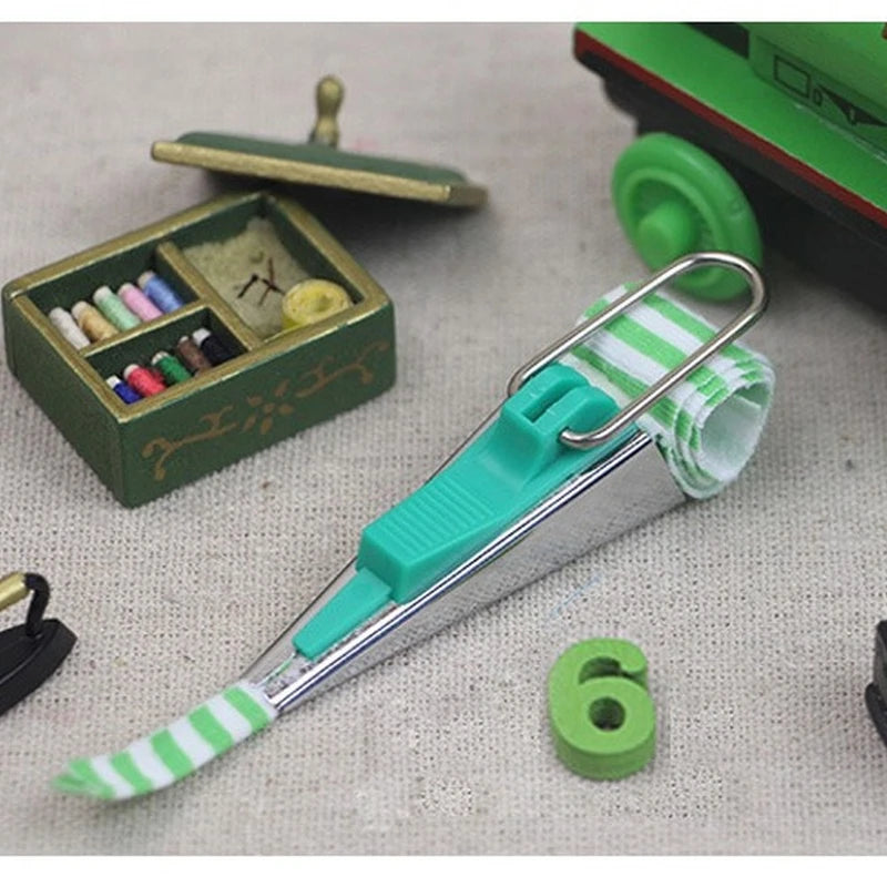 A stainless steel bias tape maker set with four different sized tapes and a green and white striped tool.