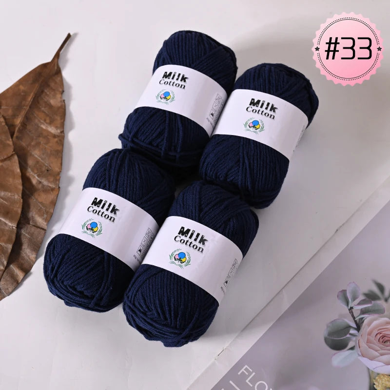 A stack of dark navy blue Milk Cotton yarn skeins with white labels and a pink tag marked #33.