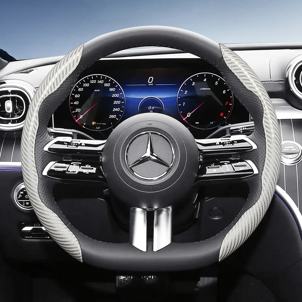 Close-up view of a black steering wheel with carbon fiber texture covers and modern instrument cluster details.