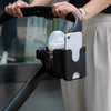 A black stroller cup holder and phone mount device is being held by a person.