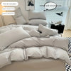 A set of soft cotton duvet cover and pillowcases in a light gray color displayed on a bed.