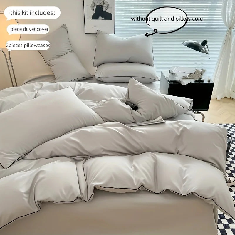 A set of soft cotton duvet cover and pillowcases in a light gray color displayed on a bed.