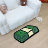 A green and yellow tufted mat shaped like a dollar bill placed on a light wood floor next to a white sofa.