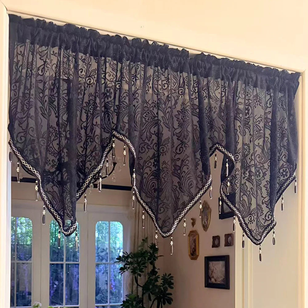 Black gothic lace curtain valance with irregular window pendants hanging in a bright room.