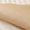 A beige plush anti-slip sofa cushion mat with a dotted texture lying on a light wooden surface.