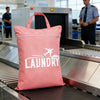 A pink laundry bag with the word LAUNDRY printed on it is placed on a conveyor belt in a facility.
