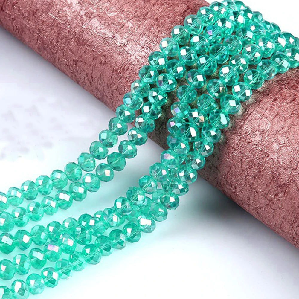 Green faceted crystal glass spacer beads strung on a pink textured ribbon.