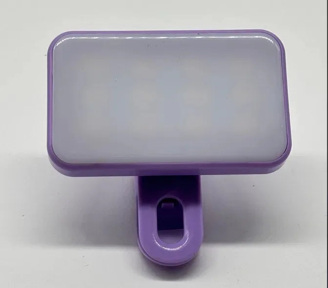 A purple clip-on LED selfie light with a rectangular translucent body and a purple mounting piece.