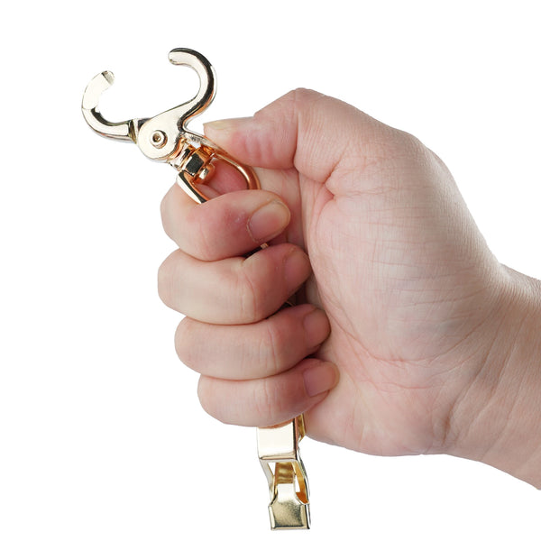 Une main tient une pince pour gant métallique robuste, montrant le mécanisme et la pince attachée.