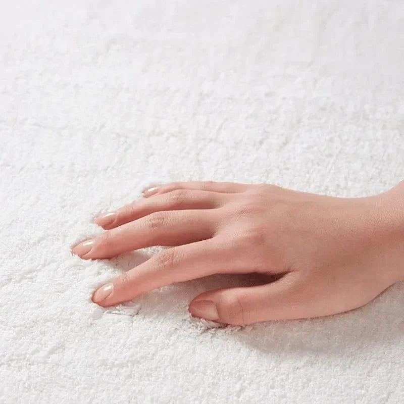A hand rests on a white fluffy mat rug.