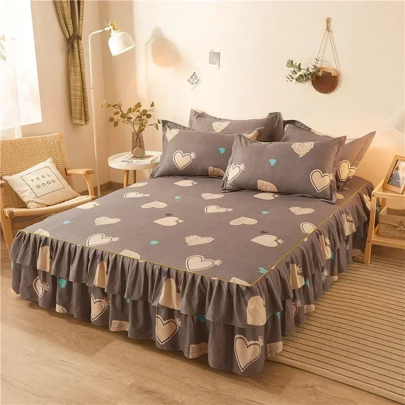 Un jupon de lit imprimé gris avec des motifs de cœurs et de feuilles blanches sur un lit.