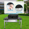 Black heavy-duty BBQ grill cover with drawstring and silver coating placed on a metal table.