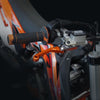 Close-up of an orange and black dirt bike handlebar featuring a CNC aluminum brake and clutch lever set.