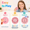 A girl is smiling while playing with a pink math spinner game that involves spinning and solving multiplication problems.