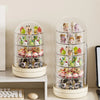 A clear rotating display case filled with small collectible figurines and keepsakes on a white shelf.