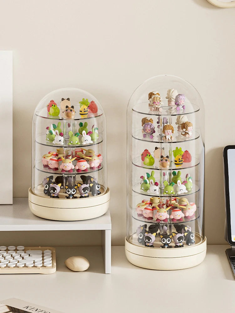 A clear rotating display case filled with small collectible figurines and keepsakes on a white shelf.