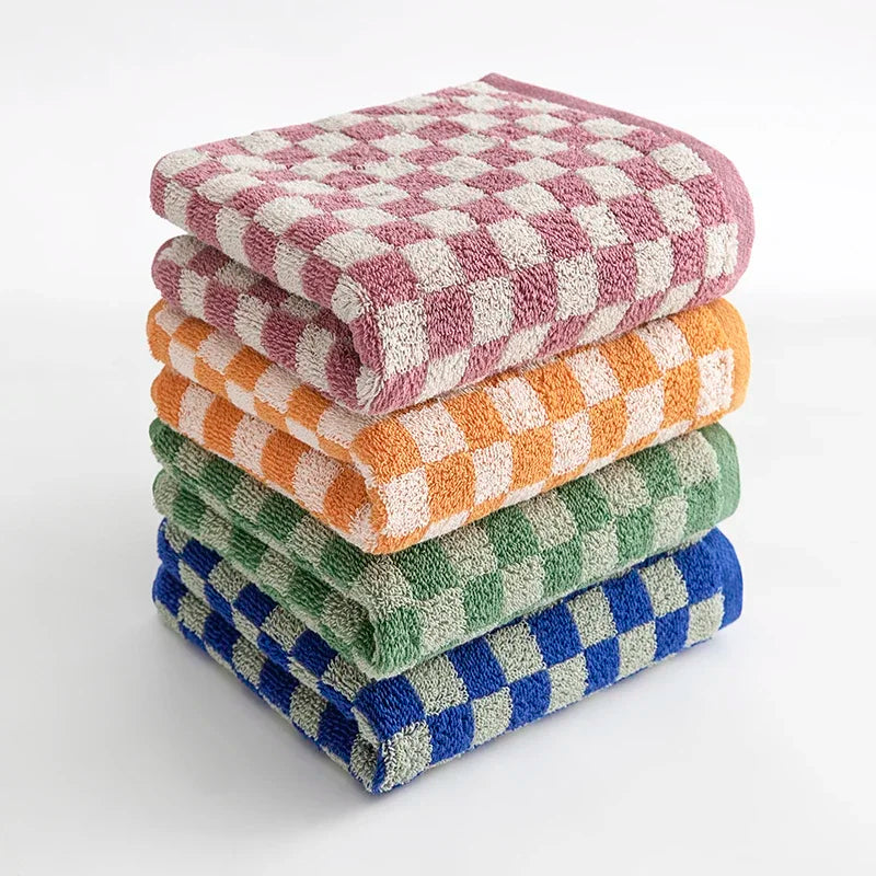A stack of soft plaid cotton bath towels in various colors including pink, orange, and green.